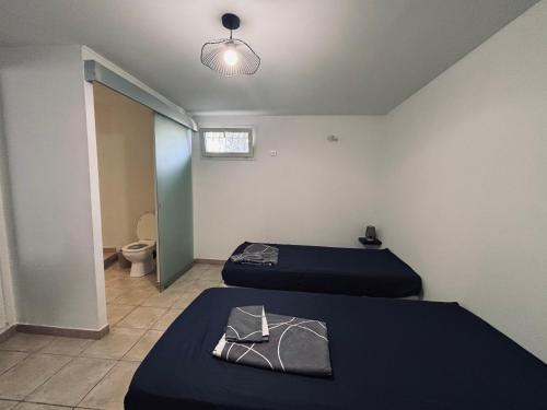 a room with two beds and a bathroom with a toilet at Le cosy d'Aramon in Aramon