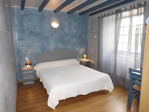 a bedroom with a white bed and a blue wall at La Maison De Suzanne in Arcomie