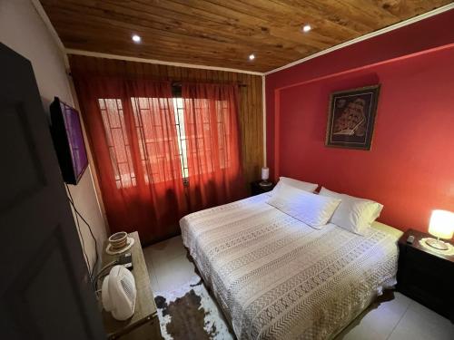 a bedroom with a red wall with a bed and a television at Hostal Rancel in Angol