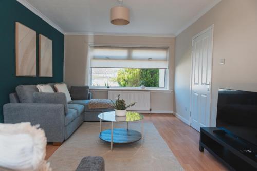 a living room with a couch and a table at The Cosy Plover in Johnstone