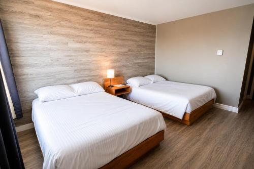 two beds in a hotel room with at Hotel Blanc-Sablon in Blanc-Sablon