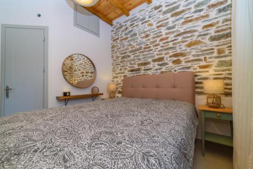 a bedroom with a bed and a stone wall at Orange House - Upper East apartment in Promírion