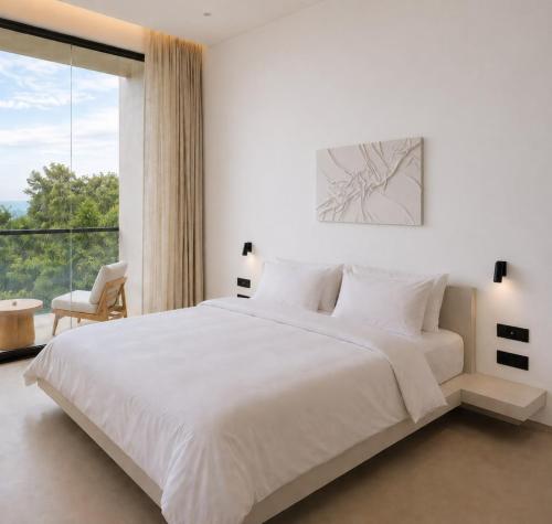 a white bedroom with a large bed and a large window at Maxx Una in Unawatuna