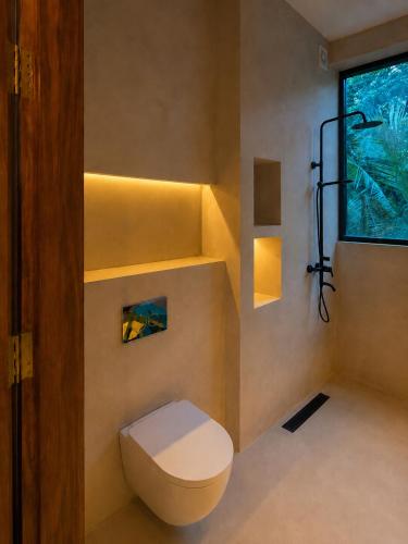a bathroom with a toilet and a window at Maxx Una in Unawatuna
