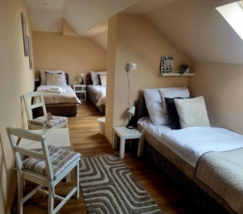 a bedroom with two beds and a chair at Határ Motel in Somoskőújfalu