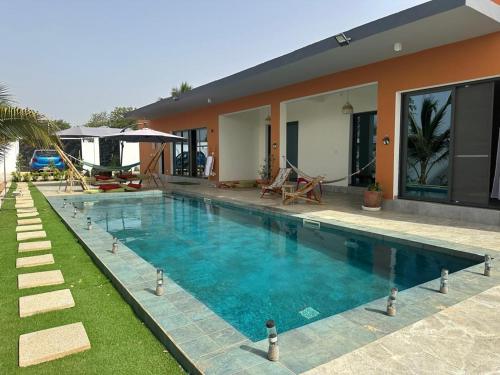 a swimming pool in front of a house at Ker Ar Mor - Villa 3 chambres avec piscine privée à Nguerigne in Sintiân