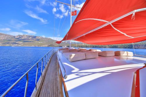 a boat with a red sail on a body of water at Blue Cruise in Kas