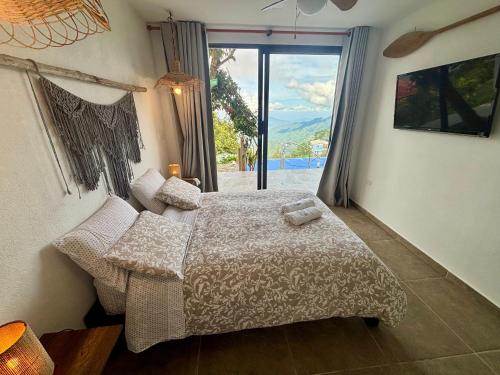 a bedroom with a bed and a large window at REFUGIO el CAMPANO in Minca
