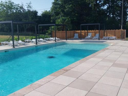 a swimming pool with blue water and chairs in it at Insolite hobbit in Saint-André-dʼAllas