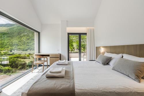 a bedroom with a large bed with a large window at Odat n'Bogë - Breakfast Included by PikHost in Bogë