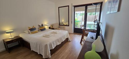 a bedroom with a large bed and a large window at At the beach with a private garden in Carcavelos