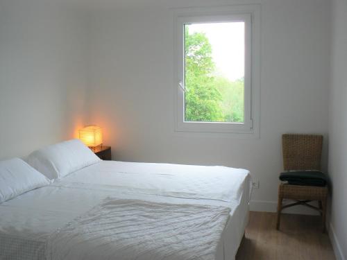 a white bedroom with a bed and a window at Maison Oyan in Urrugne