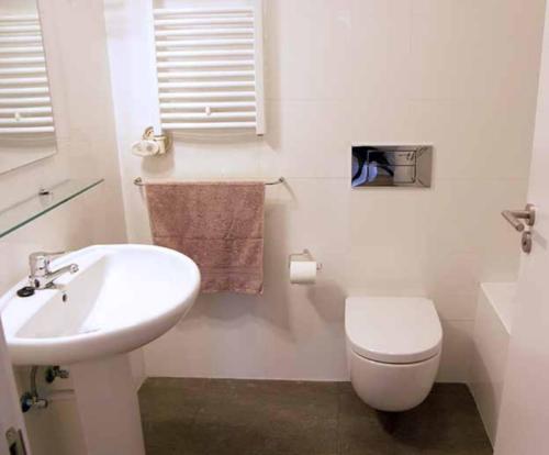 a white bathroom with a toilet and a sink at Maison Oyan in Urrugne