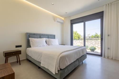 a bedroom with a large bed and a large window at Noera Villas in Kremasti