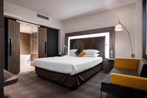 a bedroom with a large bed and a bathroom at Rénéa Hotel in Sétif