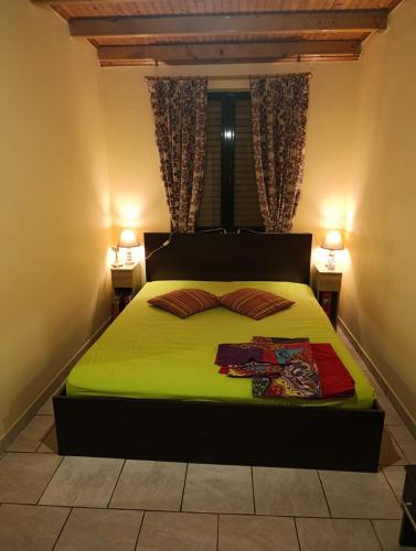 a bedroom with a bed with green sheets and two lamps at Silver SPOT Raches in Kouvéla