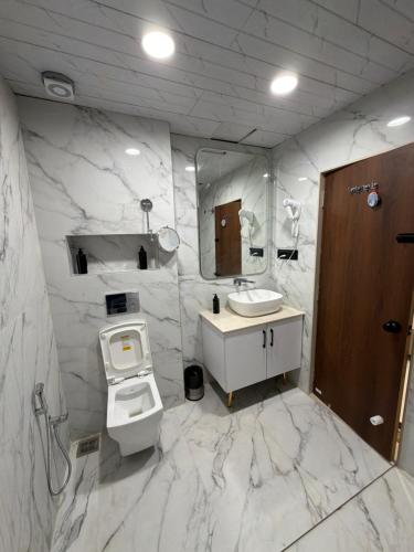 a marble bathroom with a toilet and a sink at Hotel Krishna Leela Lodging and Boarding in Bhusāwal