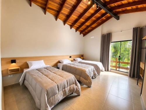 a bedroom with three beds and a large window at Pousada Estação Rio Branco in Votuverava