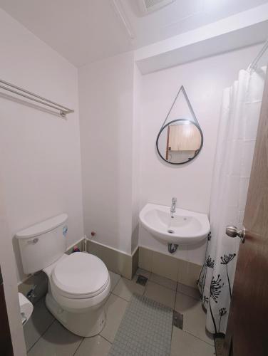 a white bathroom with a toilet and a sink at Homey Studio Apartment in Mandaue in Mandaue City
