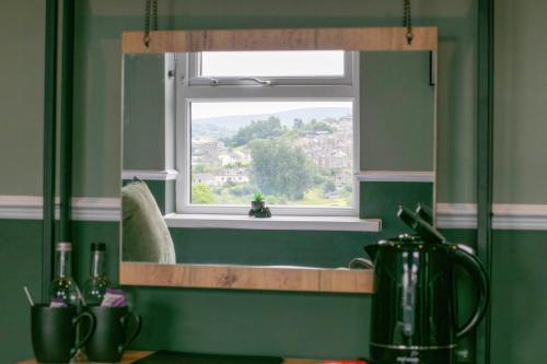 a mirror in a kitchen with a window and a sink at Bronte Breaks in Haworth
