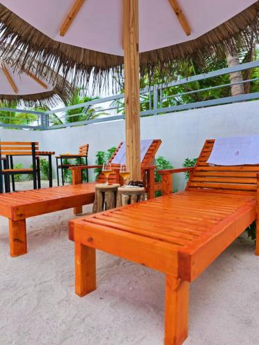 a group of wooden benches sitting under an umbrella at Ee Seaview Maldives in Vevaru