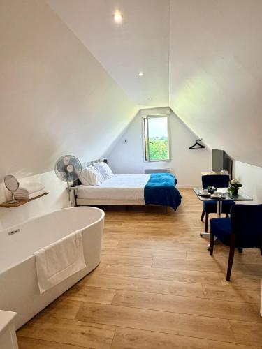 a bedroom with a bed and a tub in a room at Aux Charmes - Suites Prestige et Petit Déjeuner en chambre - Cote d Opale in Isques