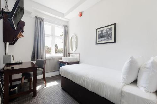 a hotel room with a bed and a desk and a window at Southern Cross in Watford