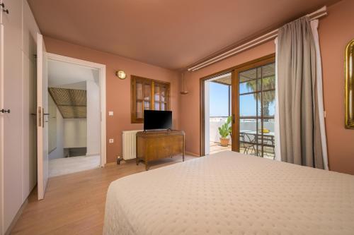 a bedroom with a bed and a television and a balcony at Old Town Tower House in Kos