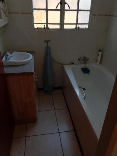 a bathroom with a bath tub and a sink at Lamenatseach 300 in Leeupoort