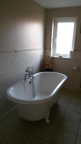 a white bath tub in a bathroom with a window at Teach Bhalor in Falcarragh