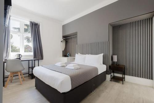 a bedroom with a large bed and a desk at Southern Cross in Watford