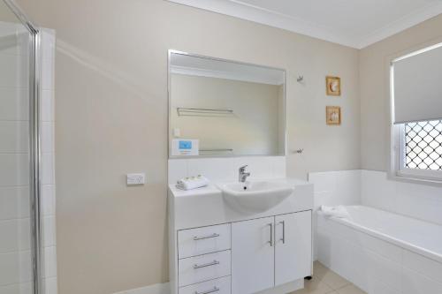 a white bathroom with a sink and a mirror at Flip Flop Inn in Amity Point