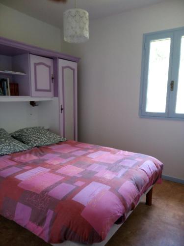 a bedroom with a bed with a pink and purple comforter at La simonde in Malarce-sur-la-Thines