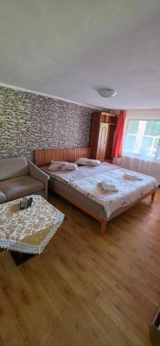 a bedroom with a large bed and a couch at Cabana Cerbu in Bozovici