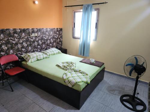 a bedroom with a bed with a green comforter and a window at Residence samy in San-Pédro
