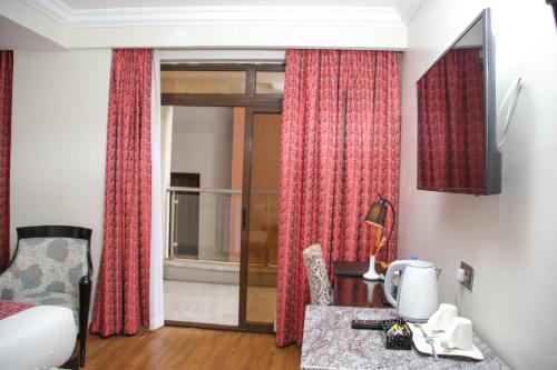 a hotel room with a bed and a desk with a chair at Eagle Palace Hotel in Nakuru