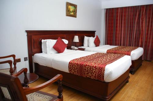 a hotel room with two beds and a chair at Eagle Palace Hotel in Nakuru