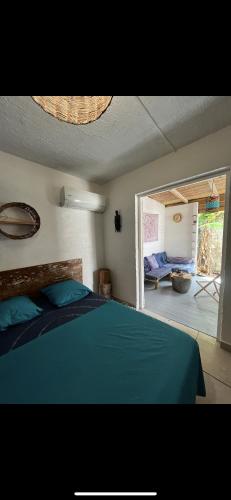 a bedroom with a blue bed and a living room at Les Chambres d'Umoja in Grand-Bourg