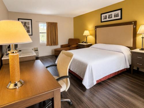 a hotel room with a bed and a desk with a lamp at Country Host Inn in Franklin