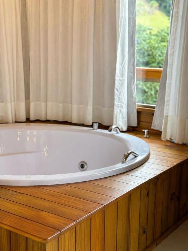 a bath tub in a room with a window at Chalé Saúde in Venda Nova do Imigrante