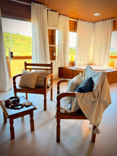 a living room with two chairs and a table at Chalé Saúde in Venda Nova do Imigrante