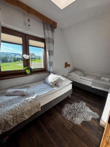 a bedroom with two beds and a window at Nase Chaty- domki z balią, termy i natura in Biały Dunajec