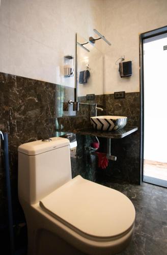 a bathroom with a white toilet and a sink at Luxury Apartment With Farm View in Siolim