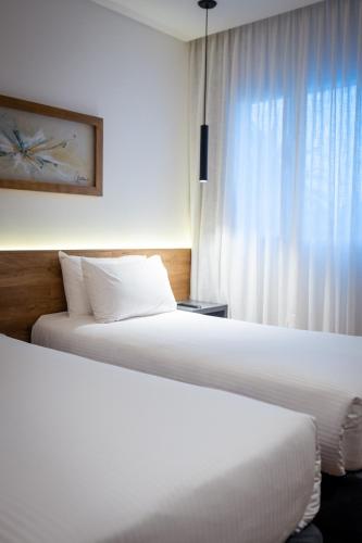 two beds in a hotel room with a window at Dazzler by Wyndham Salta in Salta
