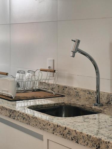 a kitchen counter with a sink and some bar stools at Bela Vista Por do Sol in Espirito Santo Do Pinhal