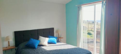 a bedroom with a bed with blue walls and a window at Cabaña lomas de chaica in Puerto Montt