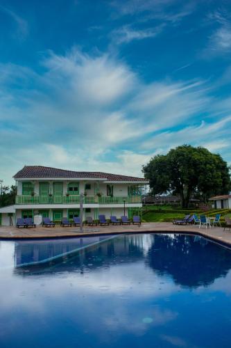 a building with a large swimming pool in front of it at Hotel Eden Parque del Cafe in Montenegro