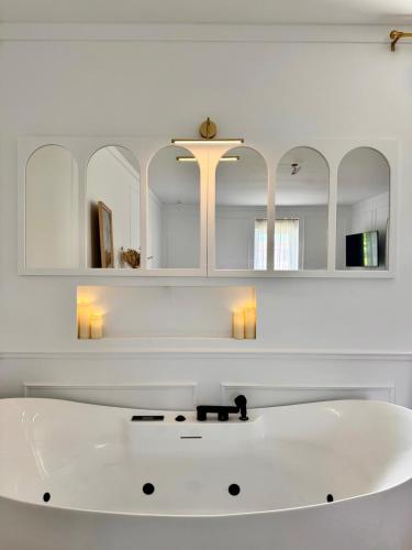 a white bathroom with a white tub and mirrors at La Folie Blanche in Vertou