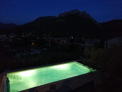 a swimming pool at night with a mountain in the background at Le mas christiane in Buis-les-Baronnies