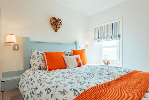 a bedroom with a large bed with orange pillows at Driftwood Cottage by Bloom Stays in Folkestone